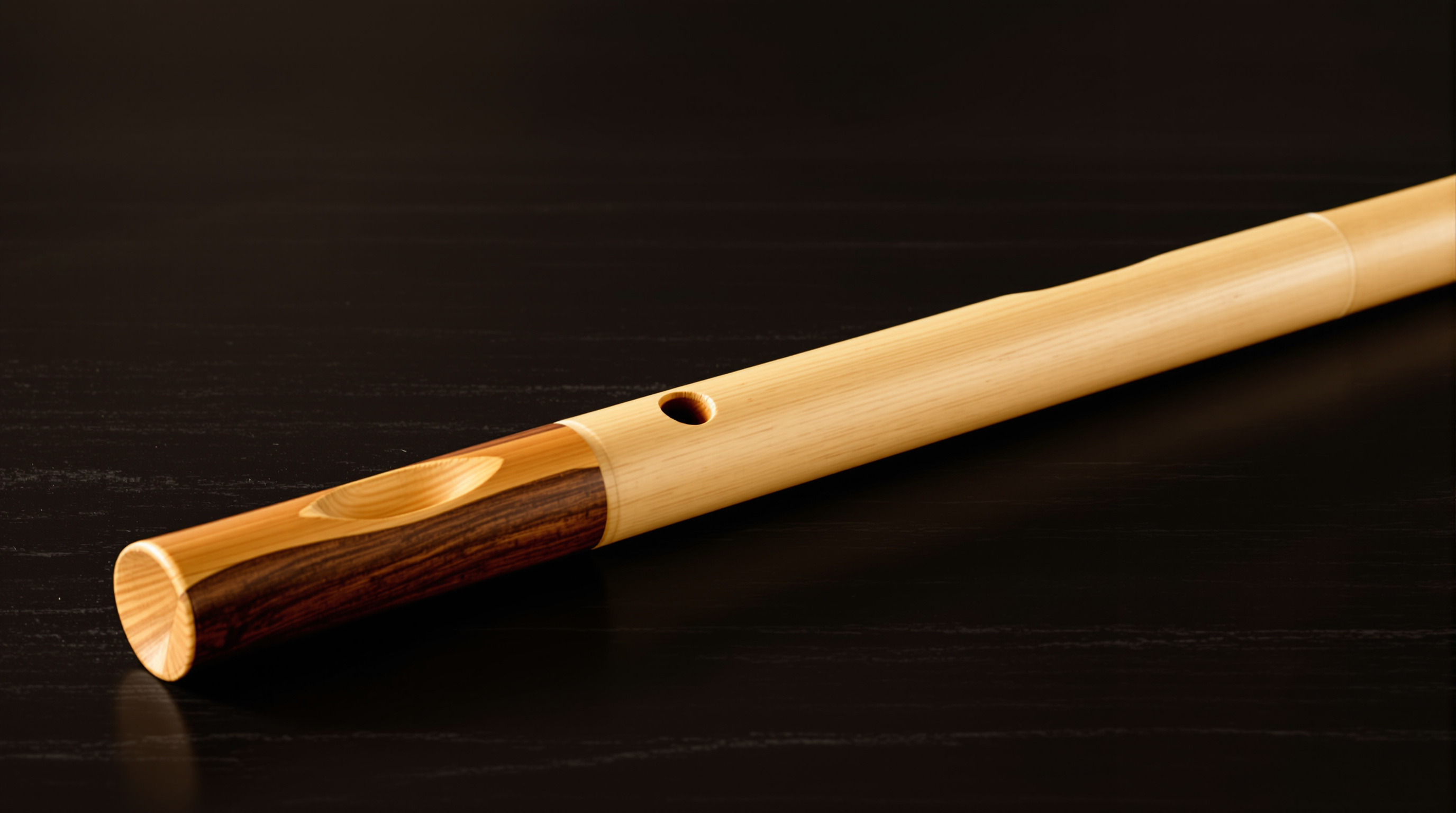 Bamboo transverse flute with a hardwood lip plate on dark wood